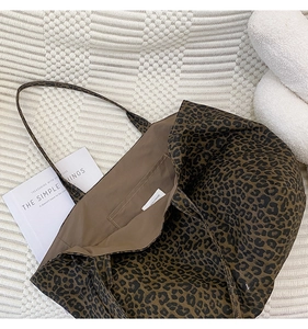 Close-up of leopard print canvas tote bag with internal open pocket on a white bed sheet