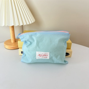 Close-up of light blue macaron makeup bag with pink zipper and brand label details
