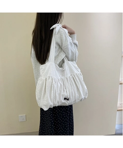 Detail of white pleated canvas tote bag with black polka dots and bow shoulder strap
