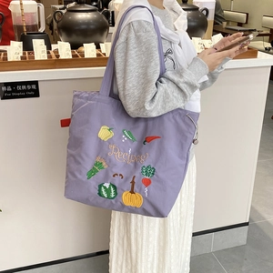 Détail de broderies légumes colorés et texte Recipes sur le sac cabas en toile mauve