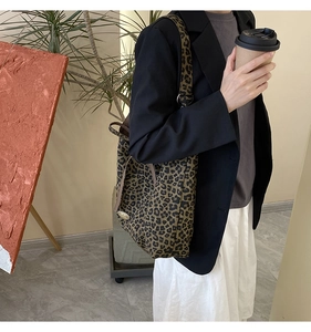 Detail of leopard print tote bag with metal buckle and shoulder strap on model