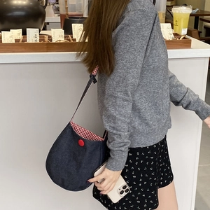 Denim shoulder bag with red plaid lining and large button detail for casual wear