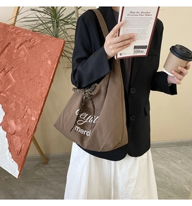 Close-up of brown canvas tote bag featuring merci print and leopard print bow decoration