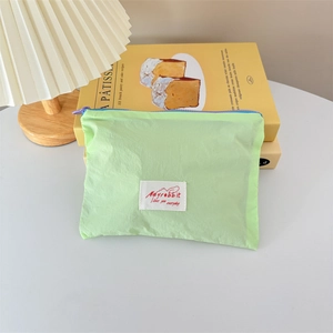 Close-up of mint green makeup pouch with Mayrabbit label on yellow books