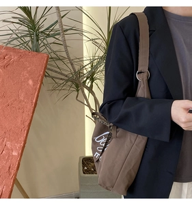 Detail of brown tote bag featuring white lettering print and leopard print ribbon accent