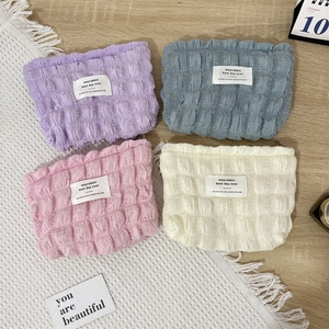Detail of colorful bubble textured canvas cosmetic bags with zipper in four soft pastel colors