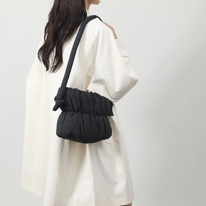 Detalle de bolso acolchado negro con textura de nube arrugada y correa ancha al hombro