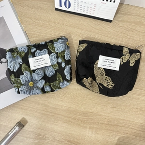 Floral and butterfly jacquard makeup bags with woven labels on light wood desk