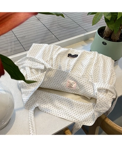 Close-up of a white polka dot tote bag with internal labels and romantic ruffles