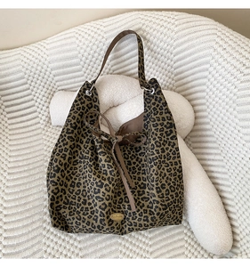 Close-up of leopard print tote bag with handmade metal tag and brown drawstring lining