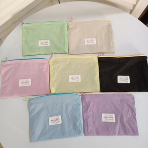 Macro shot of colorful mini nylon pouches with ring zippers and white woven labels