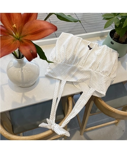 Detail of white wrap top with black polka dots featuring elegant long waist ties