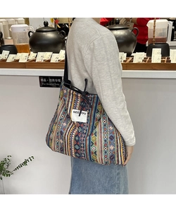 Detail of bohemian patchwork denim tote bag featuring ethnic patterns and drawstring closure