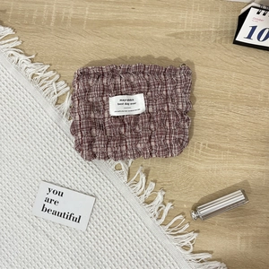 Detail of red and white checkered puff fabric storage pouch with soft texture and brand label