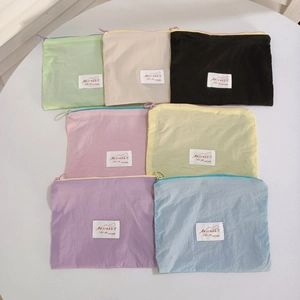 Flat lay detail of colorful mini makeup bags in seven pastel tones with white woven labels