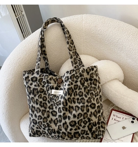 Détail du sac cabas en peluche léopard avec bouton marron et étiquette sur un canapé