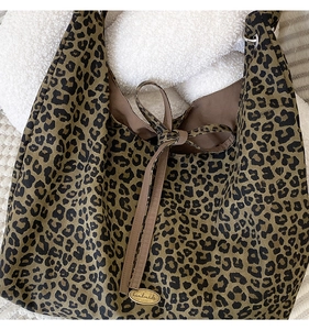 Close-up of leopard print canvas tote bag with handmade metal tag and tie closure
