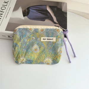 Detailed shot of canvas coin purse with peacock feather pattern and MAY RABBIT label