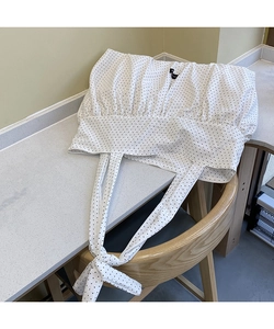Detail of white polka dot canvas tote featuring elegant knot handle and pleated texture