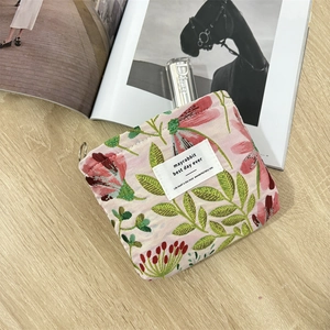 Detail of pink jacquard makeup bag with floral embroidery and white woven label