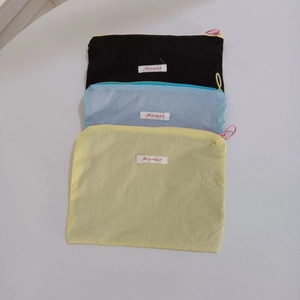 Detail of three mini macaron-colored pouches with round zip pulls and Mayrabbit labels