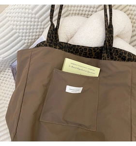 Detail of canvas tote bag showing leopard print strap and brand label on a front pocket