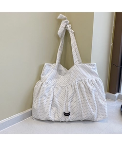 Detail of white polka dot tote bag with pleated fabric and a decorative bow shoulder strap
