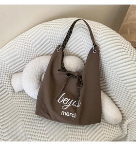 Brown tote bag detail with leopard print shoulder strap and white printed lettering