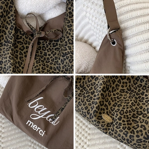 Detail view of leopard print tote bag with handmade label and bow tie ribbon accents