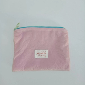 Close-up of pink mini jewelry pouch with contrast blue zipper and green ring puller