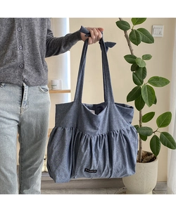 Detail of blue cotton tote bag featuring pleated canvas design and soft knotted shoulder strap