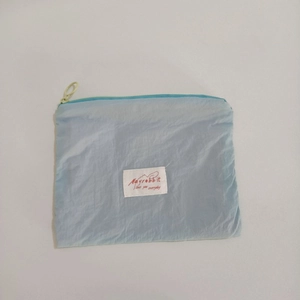 Top view of a light blue nylon makeup pouch with yellow zipper and white label
