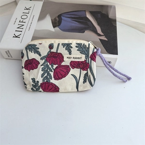 Close-up of small floral cotton coin purse with red poppy pattern and woven zipper pull
