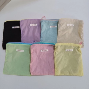 Flat lay of colorful macaron mini cosmetic pouches in nylon with white woven labels