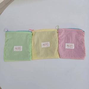 Detailed view of macaron colored nylon storage bags with zipper closure and white label