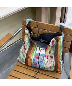 Close-up of vintage patchwork denim tote bag with floral patterns on a wooden chair