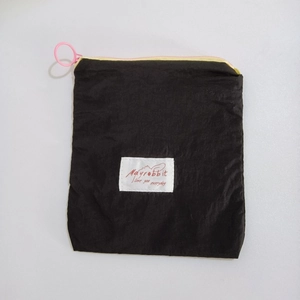 Close-up of black nylon cosmetic bag with pink ring zipper and Mayrobbit brand label