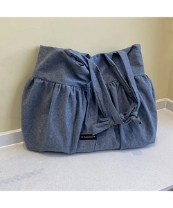 Detail of blue denim tote bag with pleated edge and Romance brand logo patch
