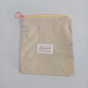 Detail of macaron beige cosmetic bag with yellow zipper and pink ring puller close-up