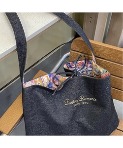 Detail of bohemian printed lining and yellow embroidery on denim shoulder tote bag