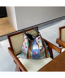 Detail of colorful floral patchwork tote bag with SEEYOU label on a vintage chair