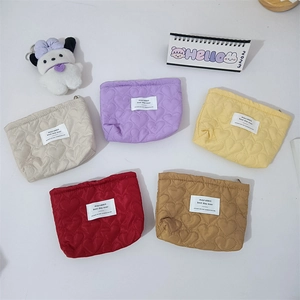 Flat lay of colorful quilted heart pattern cosmetic bags in white purple yellow red coffee