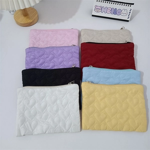 Flat lay of quilted heart pouches in eight candy colors with a desktop calendar background