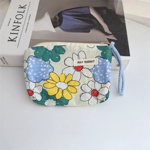 Detailed close-up of a floral cotton coin purse with zipper and light blue wrist strap