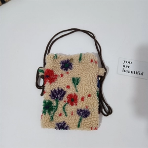 Detail view of plush mini crossbody bag featuring colorful floral embroidery and strap