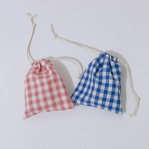Minimalist red and blue gingham drawstring storage bags in cotton fabric on white backdrop