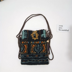 Detail of plush crossbody bag with geometric patterns, woven strap and gold bead closure