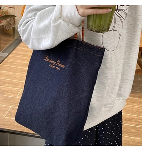 Dettaglio della borsa tote in denim con ricamo e manico intrecciato etnico