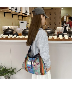 Macro view of large floral patchwork denim tote bag with colorful stripes and SEEYOU label