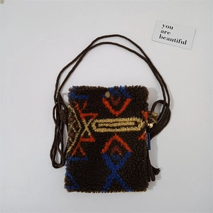 Detail of plush crossbody bag with orange and blue bohemian geometric pattern and woven strap